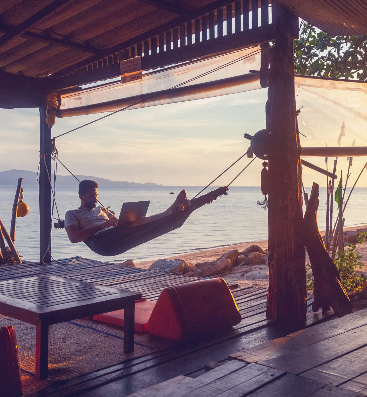 Young attractive guy a man with a beard in a hammock with a lapt man in hammock with laptop on beach