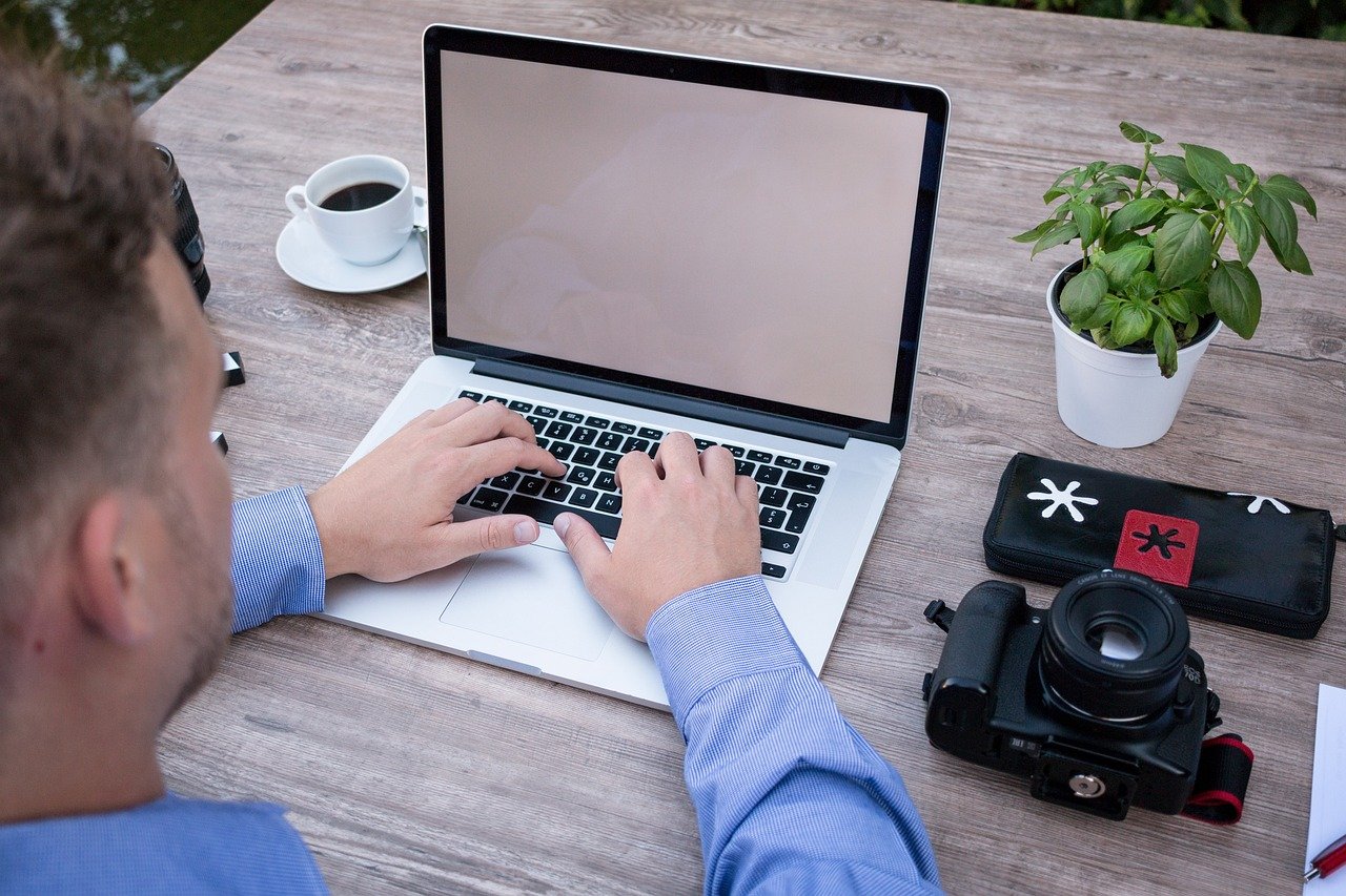 business-man-2452805-1280.jpg hand typing on laptop camera and cup of coffee an table